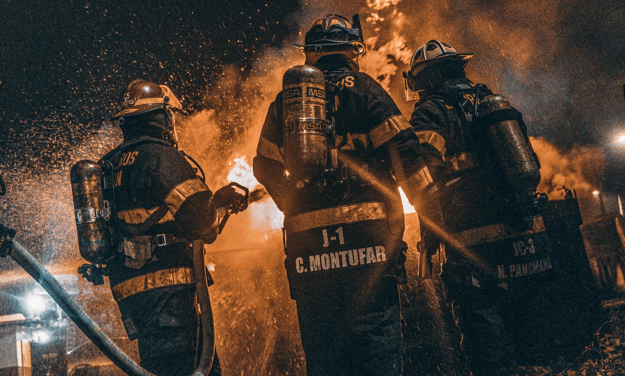 Three firefighters working together to extinguish a blaze, symbolizing accountability, clarity, and teamwork under pressure.