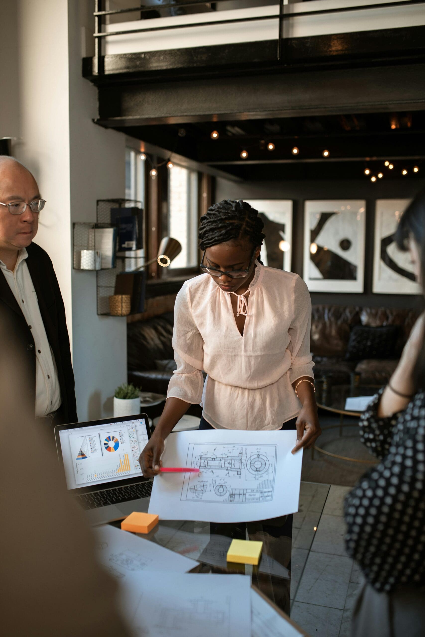 Female leader presenting technical plans to a diverse team, symbolizing knowledge-sharing and collaborative leadership.