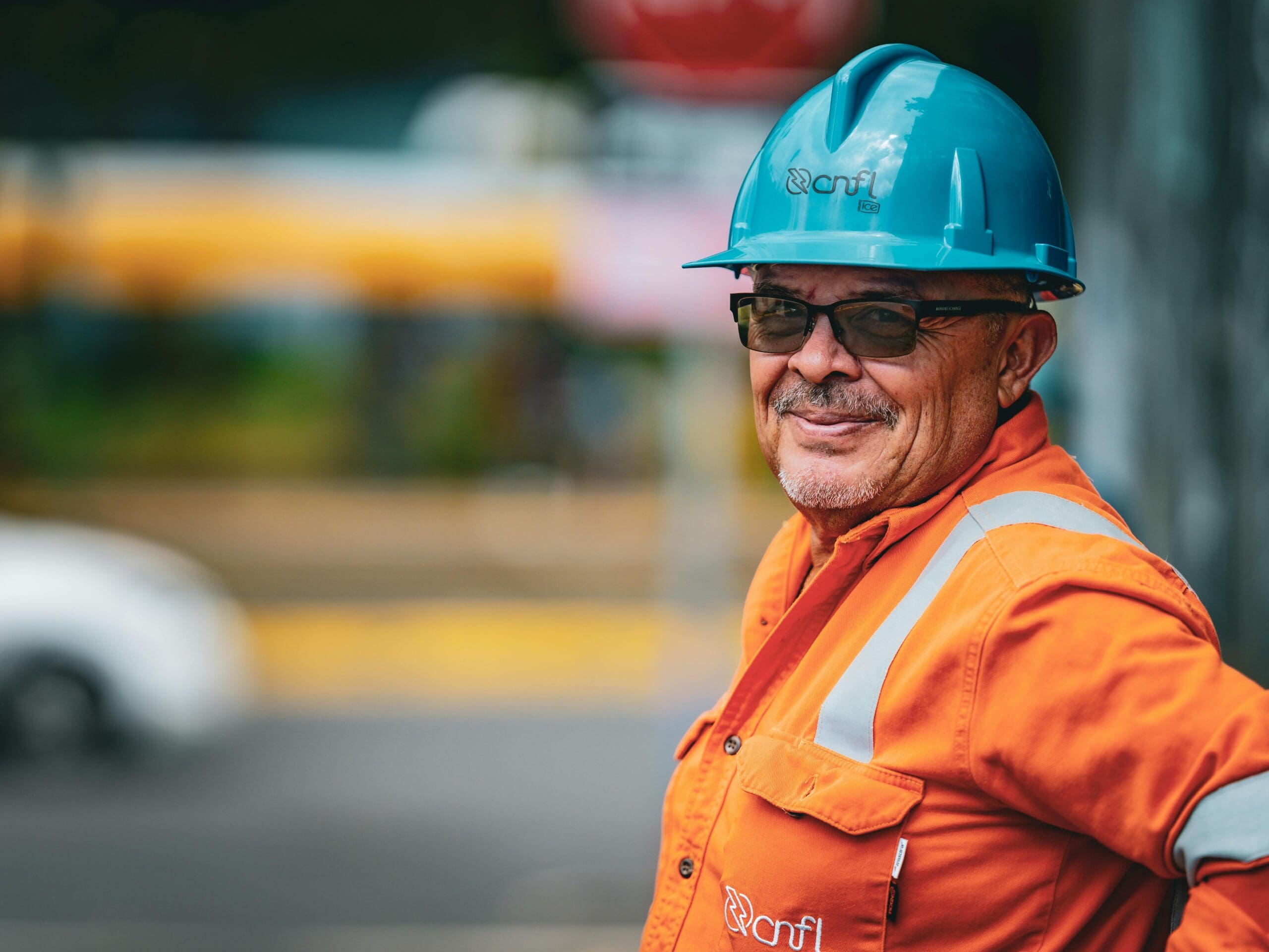 Industrial worker wearing an orange safety uniform and blue hard hat, representing leadership and respect on the job site.